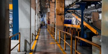 Wide view of a modern factory interior showcasing industrial machinery and conveyor systems.