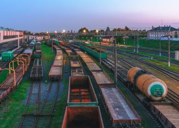 Aerial view of Minsk railway station with tracks and freight trains at dusk, highlighting transportation infrastructure.