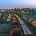 Aerial view of Minsk railway station with tracks and freight trains at dusk, highlighting transportation infrastructure.