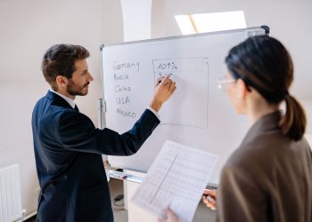 Business professionals in a meeting discussing strategies on a whiteboard.