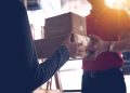 Close-up of a delivery service worker handing over packages to a customer indoors.
