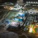A vibrant aerial shot of a construction site at night with buildings and lights.