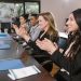 A group of smiling business professionals clapping during a seminar, showcasing success and unity.