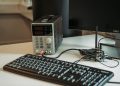 A high-tech desktop setup featuring a power programmer, computer keyboard, and monitor