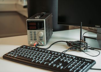 A high-tech desktop setup featuring a power programmer, computer keyboard, and monitor