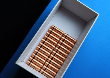 Top view of neatly arranged batteries in a box on a contrasting blue surface.
