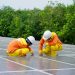 Workers installing photovoltaic solar panels on a sunny day, promoting renewable energy.