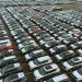 Aerial shot of an extensive car parking lot filled with new vehicles ready for distribution.