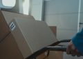 A cardboard box on a trolley inside a delivery van, showcasing logistics and shipment.