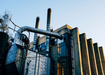 Low angle exterior of factory located on city street under blue sky in evening time