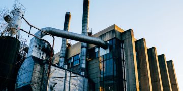 Low angle exterior of factory located on city street under blue sky in evening time