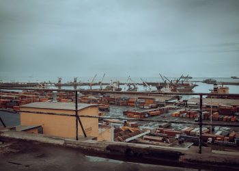 View of Tema Port in Ghana featuring shipping containers and cranes under a cloudy sky.