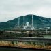 Power plant in a mountainous landscape with smokestacks emitting smoke, highlighting industrial impact on the environment.