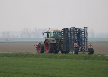 A tractor working on agricultural land during an overcast day, depicting modern farming practices.