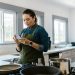 A woman in a modern kitchen following a recipe on her smartphone while cooking.