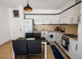 Bright modern kitchen with white cabinets, dining area, and appliances.