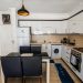 Bright modern kitchen with white cabinets, dining area, and appliances.