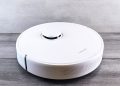 Sleek white robot vacuum cleaner on a wooden floor, perfect for smart home setups.