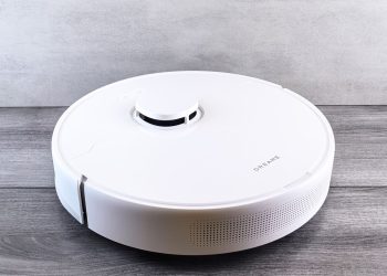 Sleek white robot vacuum cleaner on a wooden floor, perfect for smart home setups.