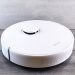 Sleek white robot vacuum cleaner on a wooden floor, perfect for smart home setups.