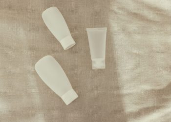 Flat lay image of minimalist plastic squeeze bottles on a textured surface.