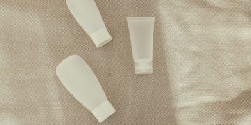 Flat lay image of minimalist plastic squeeze bottles on a textured surface.