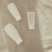 Flat lay image of minimalist plastic squeeze bottles on a textured surface.