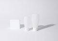 Minimalist white cosmetic containers with shadows, perfect for product mockups and ad designs.