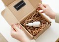 Hands opening a package with a skincare dropper bottle in protective packaging.