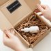 Hands opening a package with a skincare dropper bottle in protective packaging.