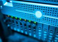 Focused view of a modern data server rack with blinking lights in a blue-lit environment.