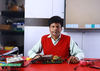 Adult male teaching electronics repair at a training institute, surrounded by circuits.