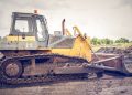 A powerful bulldozer on muddy construction ground under a cloudy sky.
