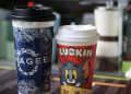 Two colorful branded coffee cups with distinct designs, indoors setting.