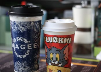 Two colorful branded coffee cups with distinct designs, indoors setting.