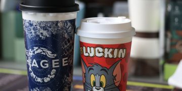 Two colorful branded coffee cups with distinct designs, indoors setting.