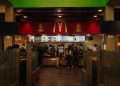 A bustling scene at a McDonald's restaurant counter with customers and staff in an indoor setting.