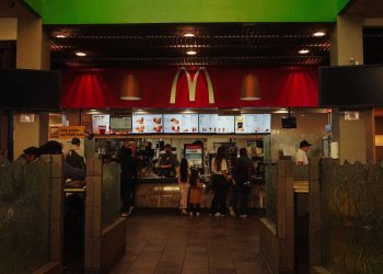 A bustling scene at a McDonald's restaurant counter with customers and staff in an indoor setting.
