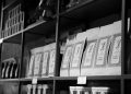 A monochrome image of coffee bags neatly arranged on a store shelf, creating an organized display.