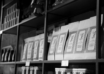 A monochrome image of coffee bags neatly arranged on a store shelf, creating an organized display.
