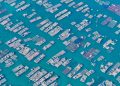 Aerial photo capturing extensive fish farms with grid-like structures in deep blue waters.