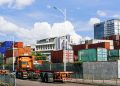 Colorful shipping containers stack at an industrial port under clear skies.
