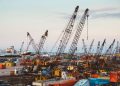 A bustling industrial port in Beirut with cranes and cargo containers.