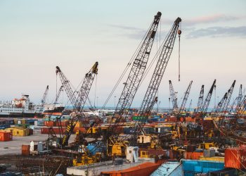 A bustling industrial port in Beirut with cranes and cargo containers.