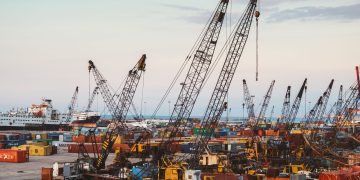 A bustling industrial port in Beirut with cranes and cargo containers.