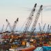 A bustling industrial port in Beirut with cranes and cargo containers.