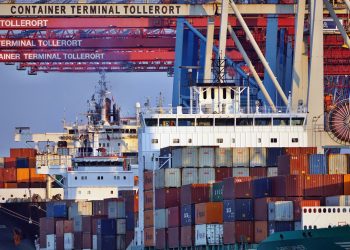 Container ships docked at Tollerort Terminal, Hamburg during sunset.