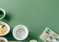 A flat lay of assorted pills and herbs on a green background emphasizing natural health remedies.