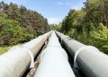 Large industrial pipeline traversing through a green forest in Geesthacht, Germany.