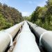 Large industrial pipeline traversing through a green forest in Geesthacht, Germany.